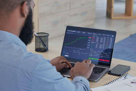 A young businessman reviews market data on a laptop. 